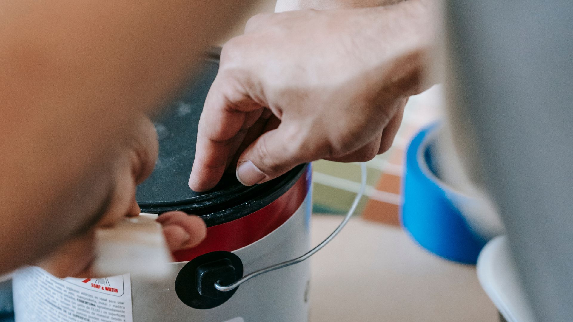 A Man Opening A Can Of Paint