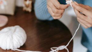 A Person Crocheting Near the Wooden Table