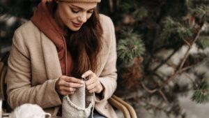 A Woman in a Brown Hoodie Knitting