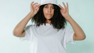 A Woman in a White T-shirt Posing While Holding her Bucket Hat