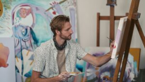 An Artist Painting on a Canvas while Holding a Color Palette