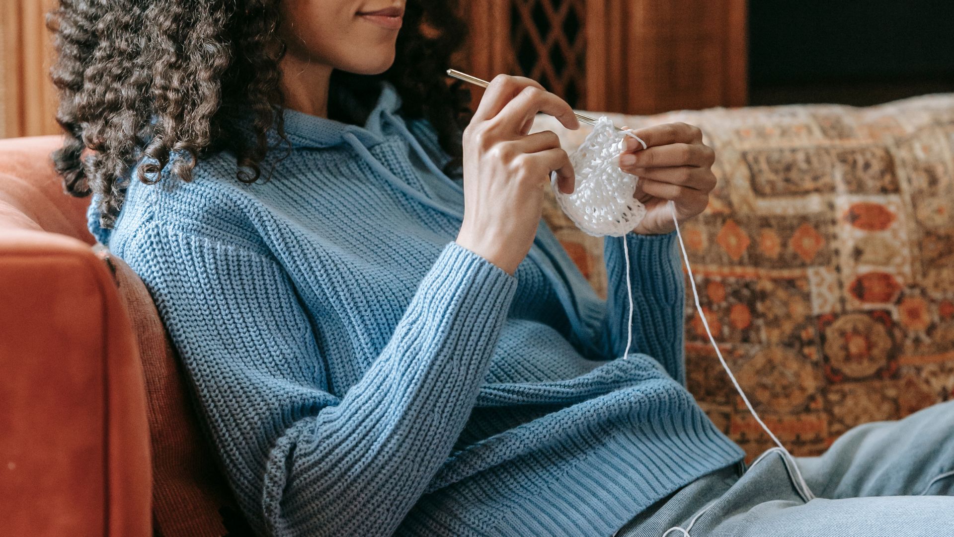 Black woman knitting on sofa