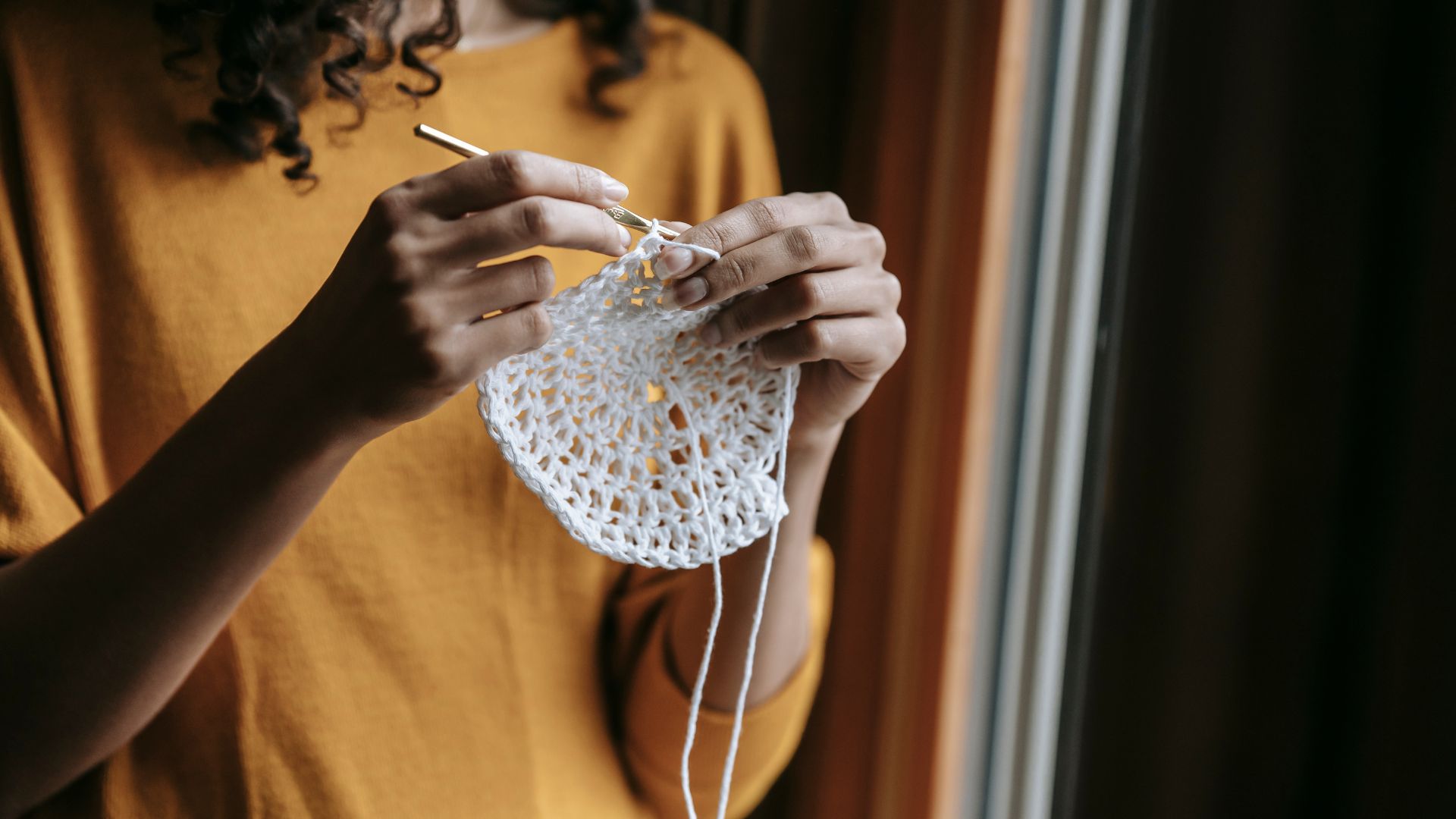 Crop craftswoman with hook crocheting at home