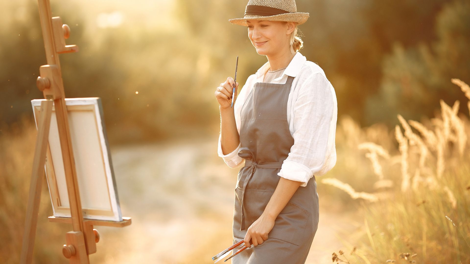 Happy artist admiring own painting in field