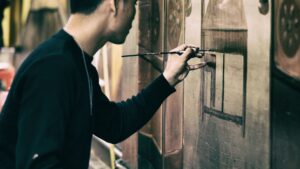 Man In Black Sweatshirt Holding Black Paint Brush Painting the Wall