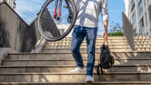 Man in White Dress Shirt and Blue Denim Jeans Standing Beside Black Bicycle