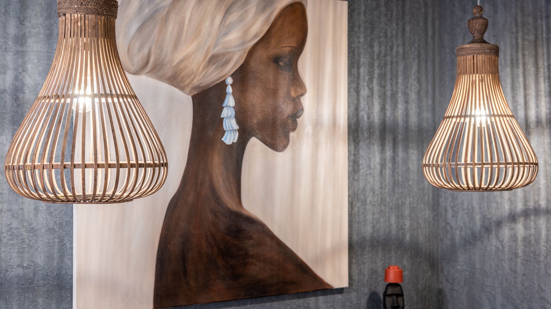 Painting of African woman on wall between shiny lamps