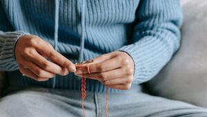 Person Holding Purple Crochet Hook .