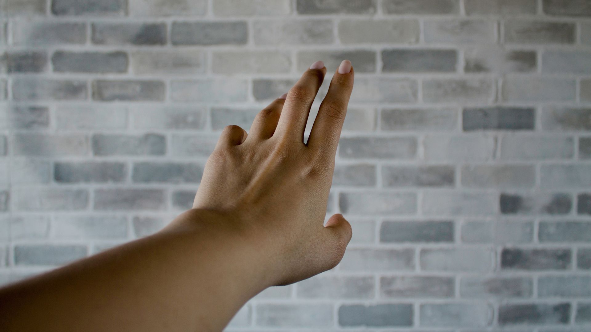 Person's Left Hand Near Gray Cinder Bricks