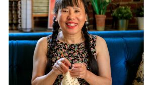 Smiling Woman Crocheting on Sofa