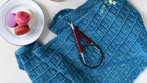 Top View of Crochet with Blue Knitwear and Macaroons on White Table