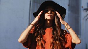 Woman Wearing Brown Shirt and Sun hat Beside White Wall