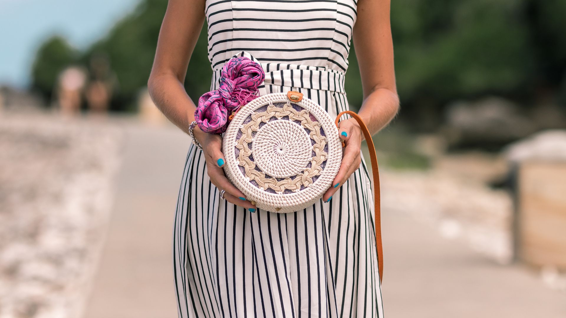 Woman Wearing White And Black Striped Sleeveless Dress Holding Round Crochet Bag