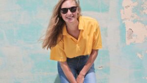 Woman Wearing Yellow Polo Shirt Standing in Front of Teal Concrete Wall