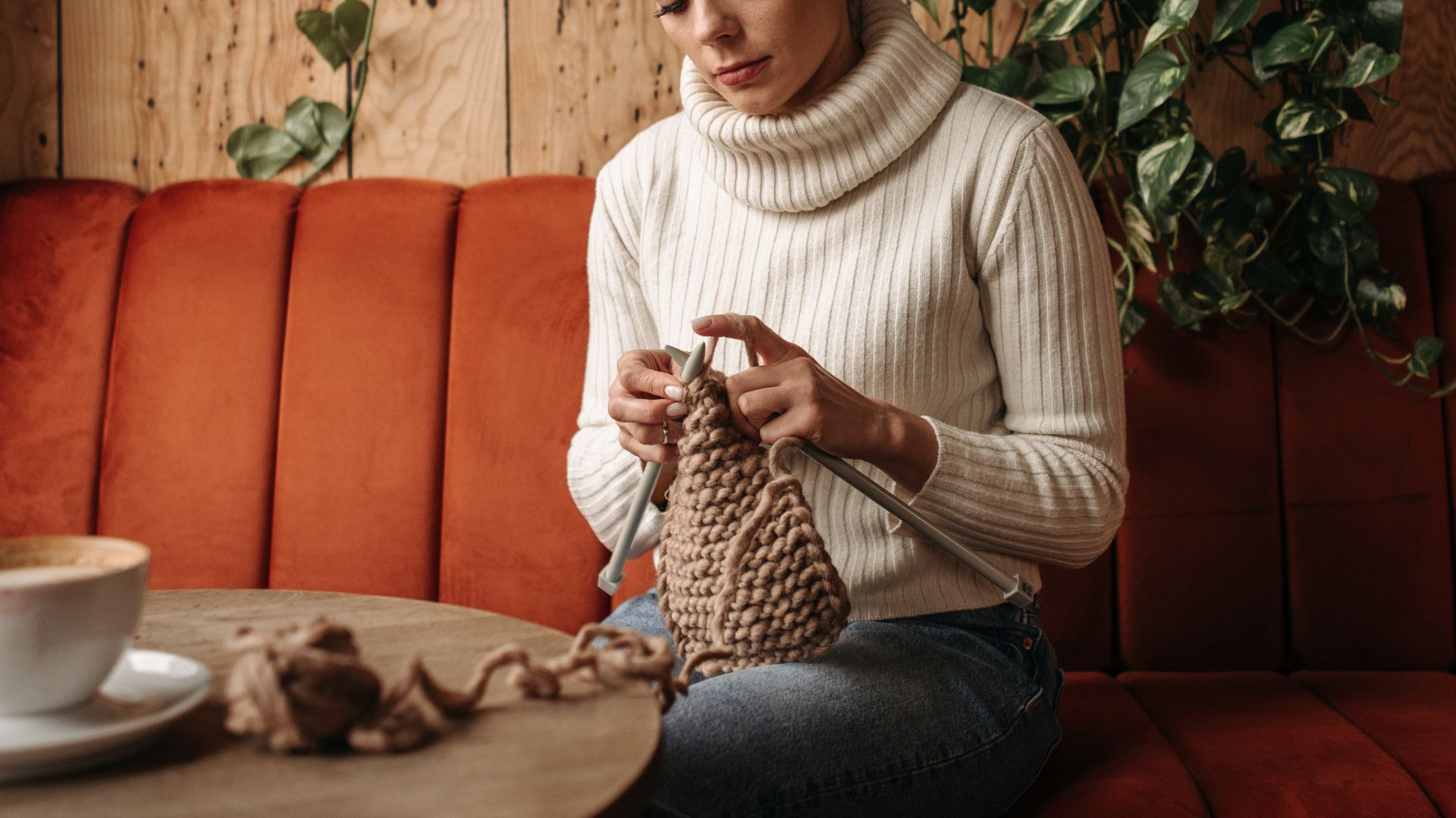 Woman in Sweater Sitting on a Couch Knitting