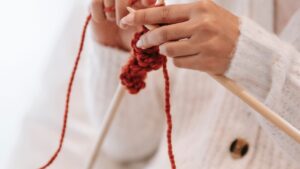 Woman knitting with woolen yarn and needles