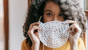 Young woman covering mouth with white crochet napkin ,.